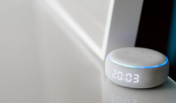 Close-up of a smart home device with a digital clock display on a white surface, illustrating how to clean smart devices safely without causing damage.