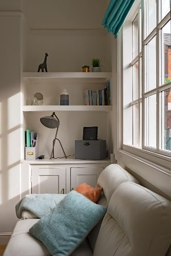 Bright and clean living space after professional end of tenancy cleaning in Kensal Green, NW10, featuring a cozy sofa, decorative pillows, and organized shelving.