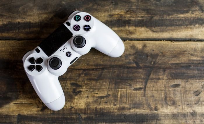 A white game controller on a wooden surface, emphasizing the importance of cleaning frequently touched devices like remotes and controllers to prevent the buildup of bacteria and the spread of harmful germs.