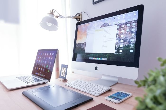 A workspace with multiple electronic devices, including a desktop monitor, laptop, and tablet, highlighting the importance of cleaning delicate screens and surfaces gently.