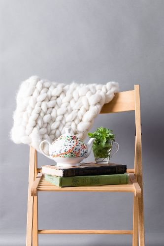 Wooden chair with a cozy throw, teapot, and houseplant in East Sheen, SW14, illustrating a freshly cleaned living space by Samyx Cleaning.