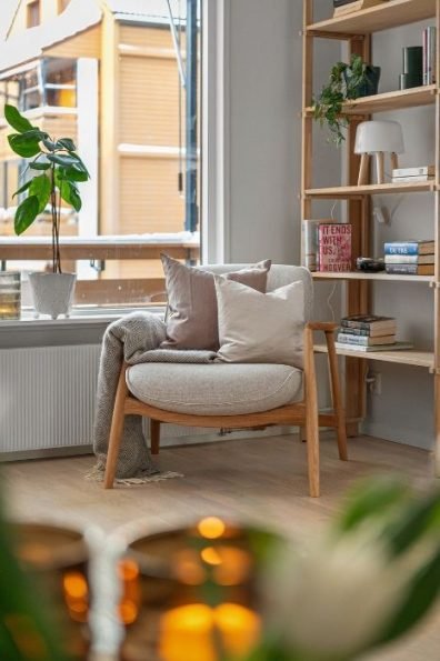 A cozy and stylish reading corner with a wooden armchair, soft cushions, and a bookshelf, representing a professionally cleaned home in Mortlake, SW14.