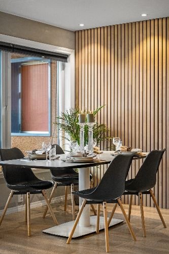 Modern dining room with elegant table setting and wooden panel wall, representing a clean and well-maintained home in Wandsworth, SW18.